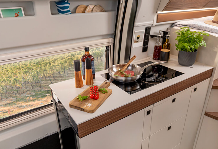 Westfalia Sven Hedin Anniversary Edition kitchenette with induction hob, steak in pan and fresh tomatoes