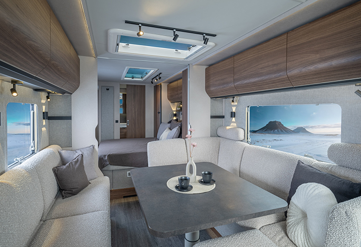 Knaus Nordwind caravan interior with lounge seating, dining table, skylights and mountain view through windows