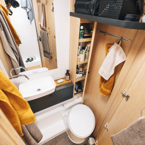 Compact bathroom in the Sunlight UNLTD T camper with cassette toilet, sink and storage shelves for Unlimited Sunlight travel.
