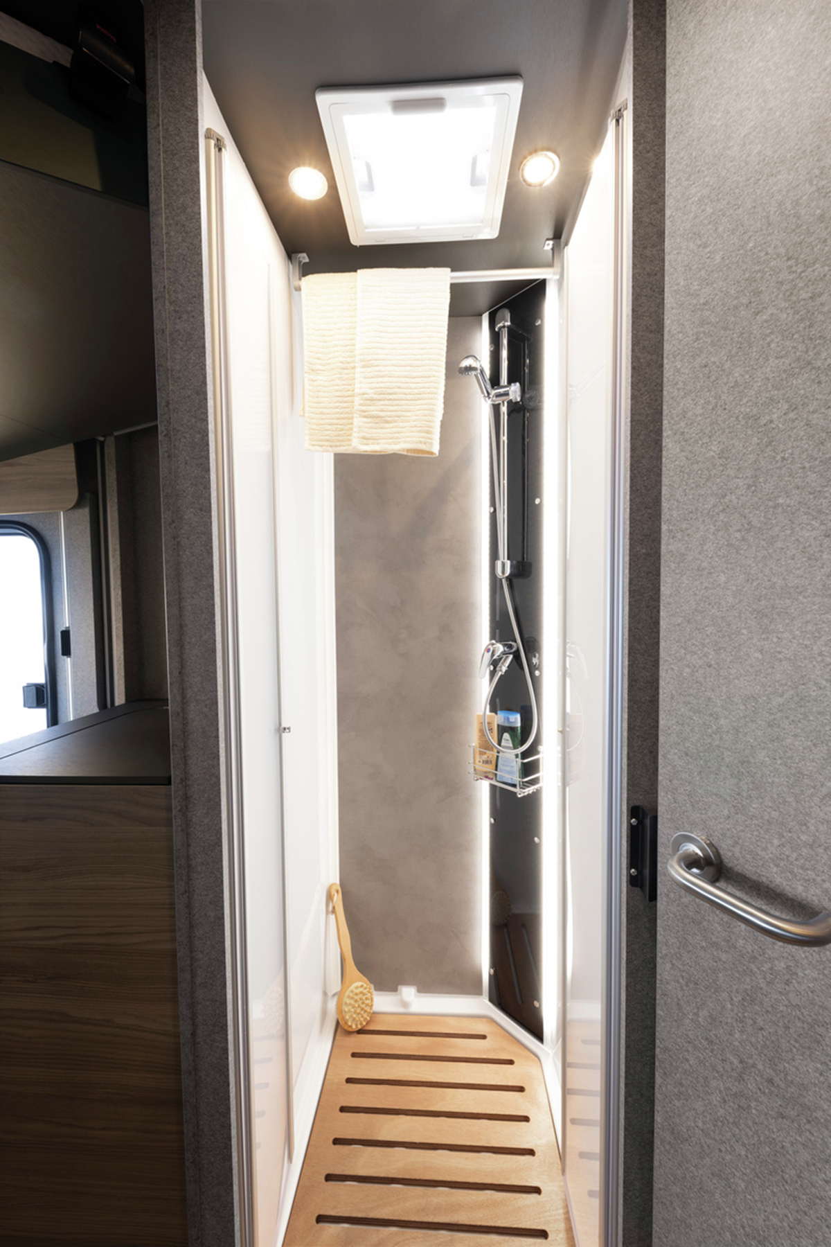Compact shower cubicle with skylight and shower caddy in the Dethleffs Trend I 7027 motorhome bathroom.