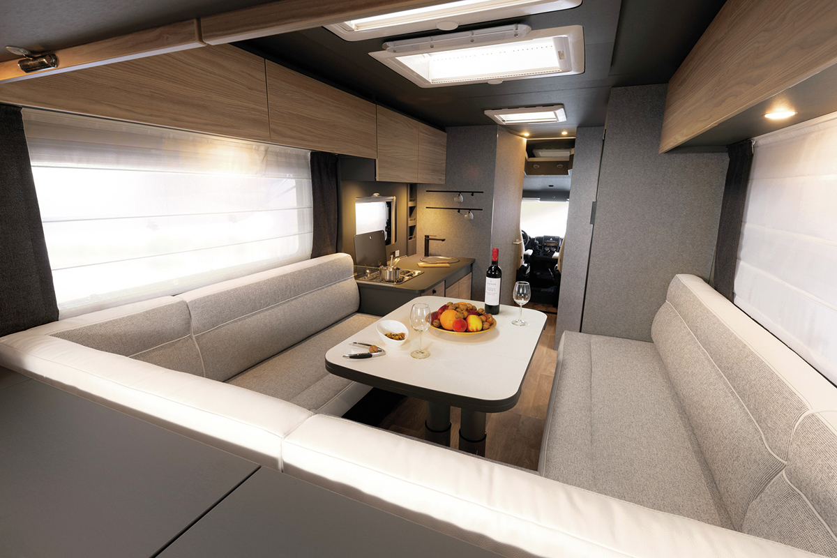 Dethleffs Trend I 7027 interior with U-shaped rear seating, dining table and kitchenette leading to cab.
