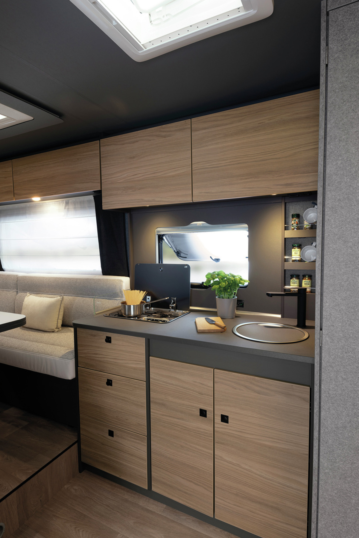 Compact kitchen with wooden cabinets, gas hob and sink in the Dethleffs Trend I 7027 caravan interior.