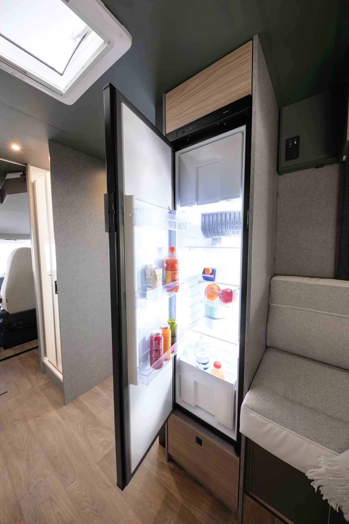 Open fridge with drinks and fruit in the Dethleffs Trend I 7027 motorhome kitchen area