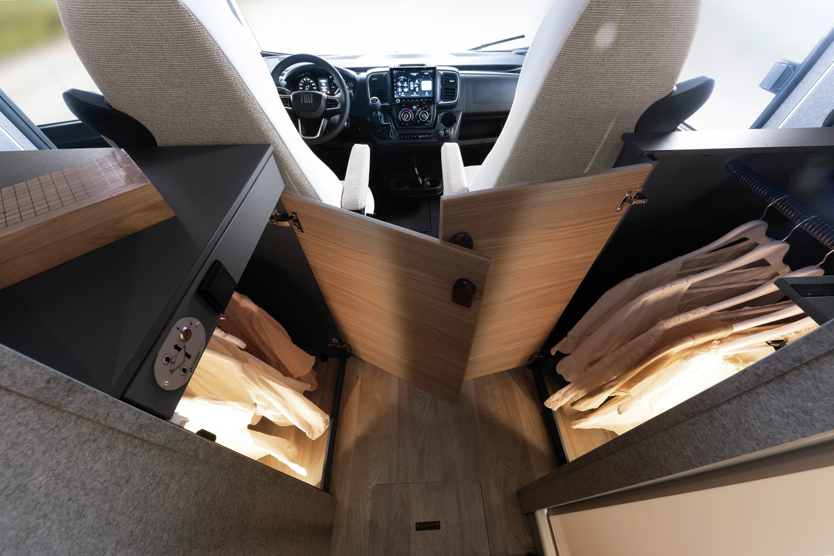 Dethleffs Trend I 7027 motorhome cab wardrobe storage with clothes hanging, seen from rear towards driver and passenger seats