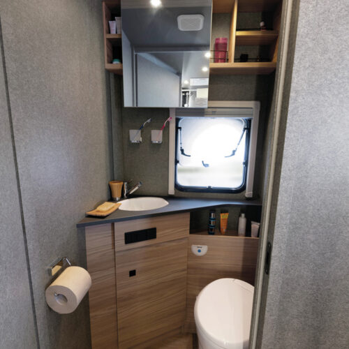 Compact washroom in the Dethleffs Trend I 7027 with toilet, corner sink, mirrored cabinet and roof vent.