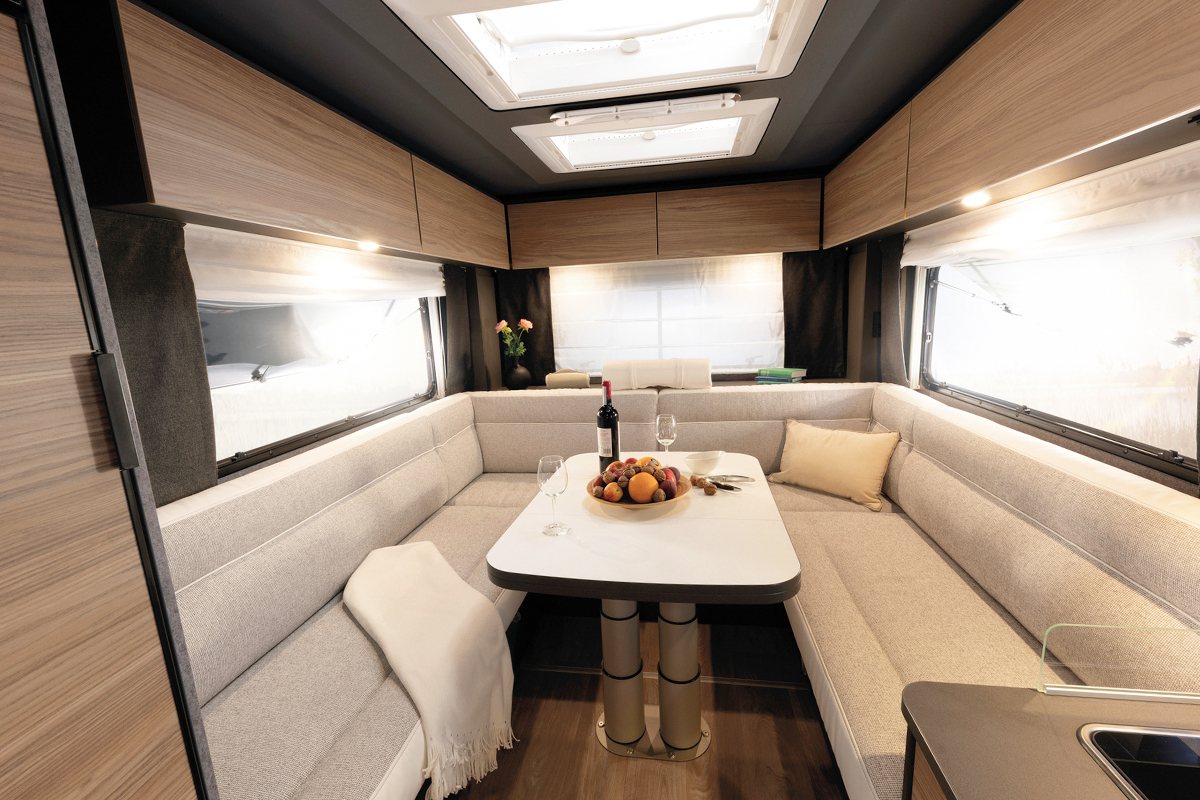 Dethleffs Trend I 7027 rear U-shaped seating area with dining table, skylights and wood-panelled interior