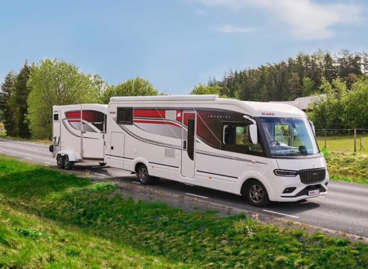 Kabe Imperial 4x4 motorhome towing a matching trailer on a countryside road with trees and a horse in the field