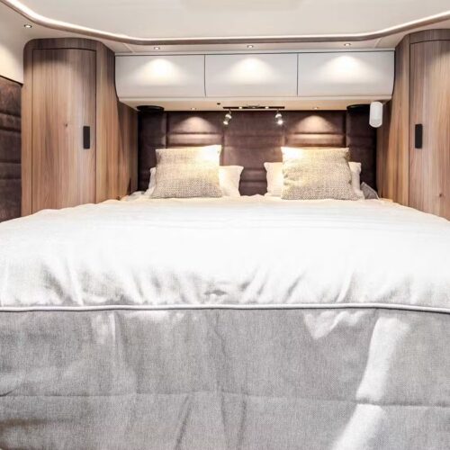 Kabe Imperial 4x4 motorhome bedroom with double bed, wood-panelled walls and overhead storage lockers