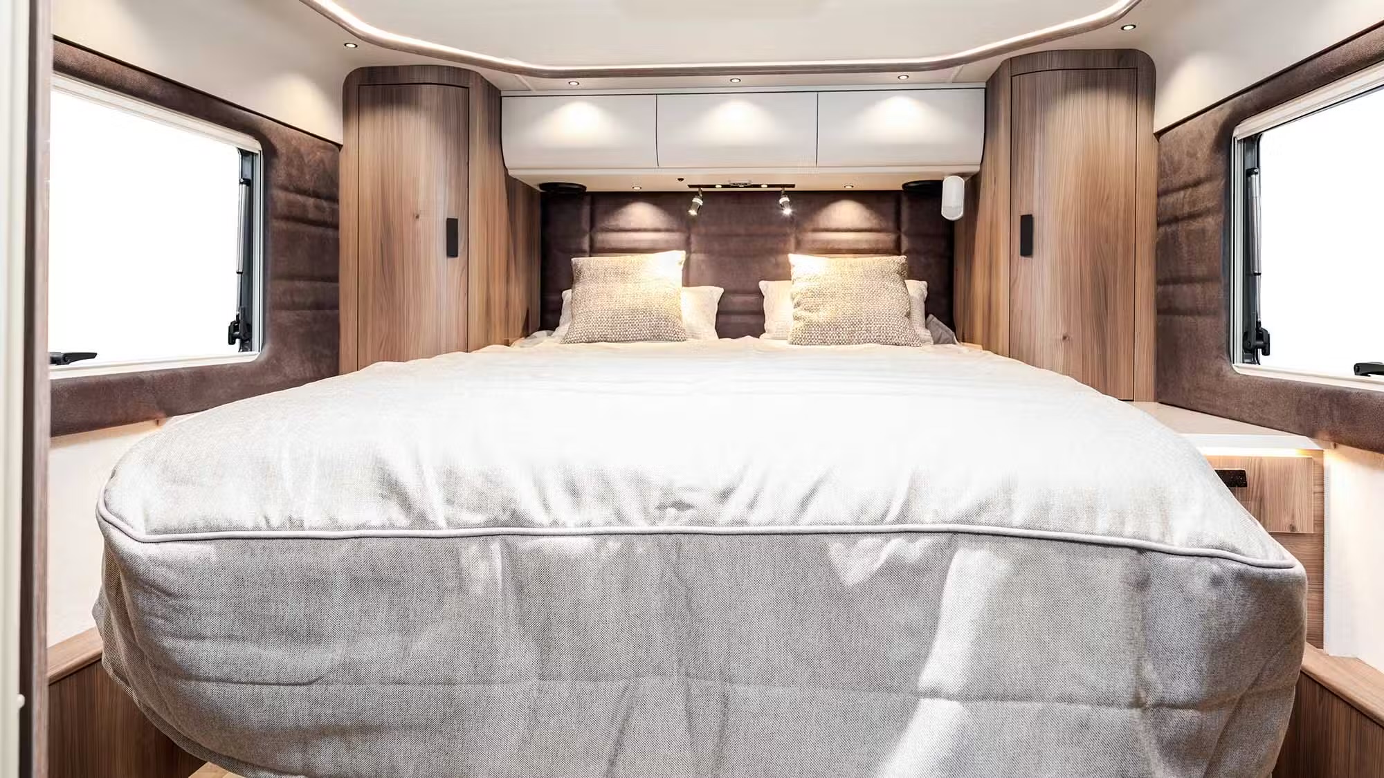 Kabe Imperial 4x4 motorhome bedroom with double bed, wood-panelled walls and overhead storage lockers