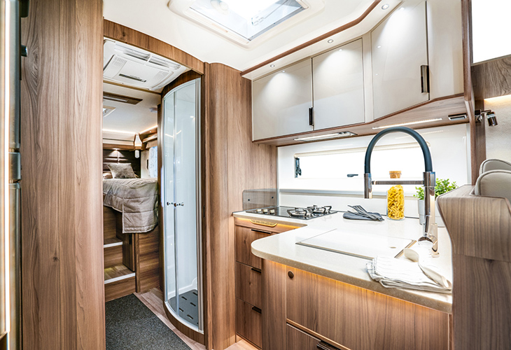 Kabe Imperial Ri810 LGB motorhome kitchen with wooden cabinetry, tap, hob and shower cubicle beyond