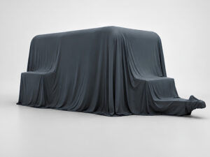 Dark grey fabric cover draped over new Lume caravan model, concealing its shape ahead of official reveal.