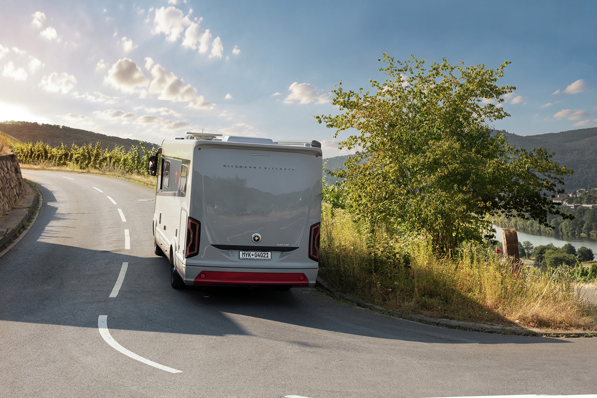 Niesmann+Bischoff iSmove 2027 motorhome rear view on a scenic winding road overlooking a river valley