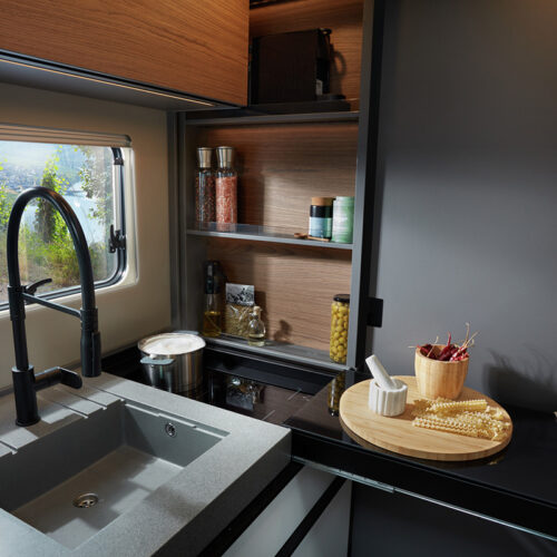 Niesmann+Bischoff iSmove 2027 kitchen with sink, hob, wooden shelving and vineyard view through window