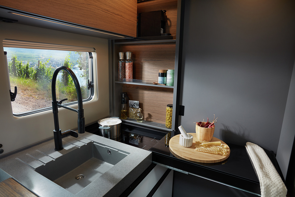Niesmann+Bischoff iSmove 2027 kitchen with sink, hob, wooden shelving and vineyard view through window
