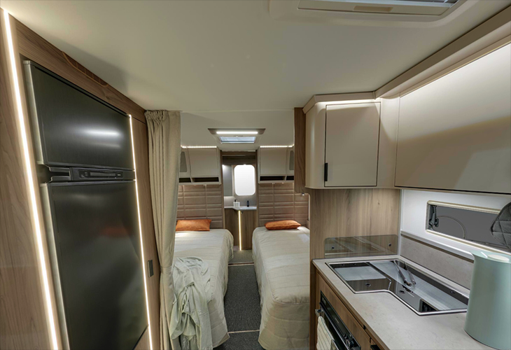 Kabe Royal 600 TDL interior showing twin single beds, kitchenette and fridge in a compact caravan layout.
