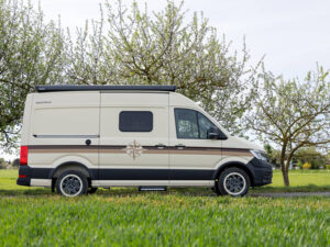 Westfalia Sven Hedin Anniversary Edition camper van parked on grass, side view showing compass emblem and stripe design