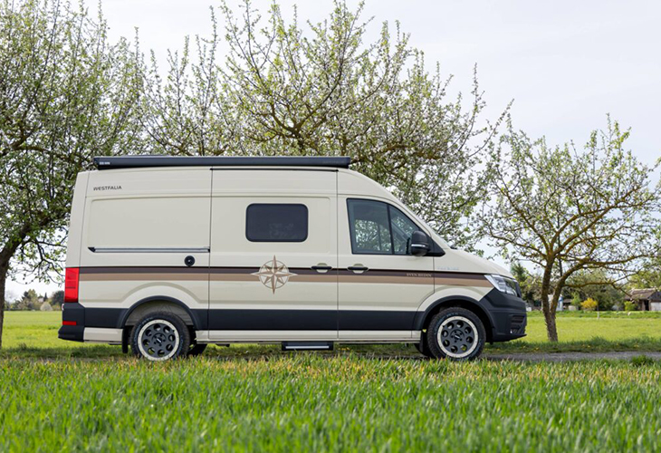 Westfalia Sven Hedin Anniversary Edition camper van parked on grass, side view showing compass emblem and stripe design