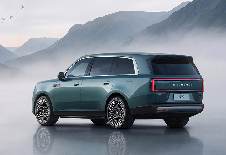 Rear three-quarter view of the Xiaomi Sky Nomad N90 SUV with illuminated taillight bar, parked amid misty mountains.