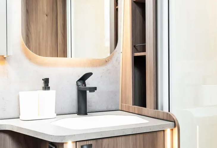 Kabe Royal 600 TDL bathroom with black tap, backlit mirror and wooden cabinetry above the washbasin