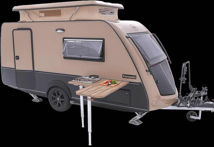 Kip Kompakt pop-top caravan with fold-out outdoor kitchen table, hob, and chopping board attached to the side.
