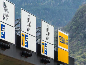 Brenner Autobahn toll booths A22 with overhead signs and Telepass lane, forested mountains behind