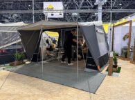 Camp-let Alba tent trailer set up at trade show with awning, groundsheet and two people inside