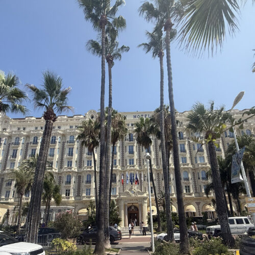 Carlton Hotel Cannes façade framed by tall palm trees, near Camping Parc Bellevue on the Côte d'Azur
