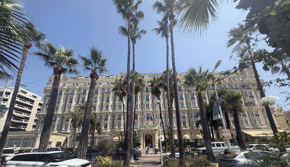 Carlton Hotel Cannes façade framed by tall palm trees, near Camping Parc Bellevue on the Côte d'Azur