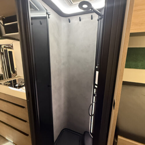 Compact shower cubicle in the Frankia Noctra Liner, featuring skylight, rain showerhead and grey stone-effect walls.