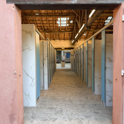 Shower block corridor with marble-effect cubicles at Camping Parc Bellevue Cannes, under a wooden beamed roof