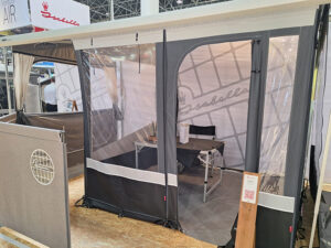 Isabella cassette awning display with mesh windows, table and chairs set up at trade show exhibition