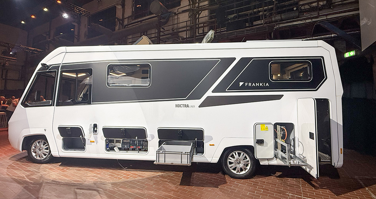 Side view of the Frankia Noctra Liner A-class motorhome showing open storage compartments and sleek black-white exterior design.