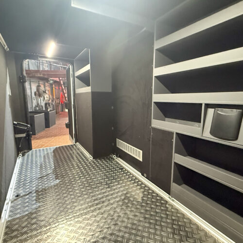 Garage storage area with shelving units and diamond-plate flooring in the Frankia Noctra Liner motorhome.