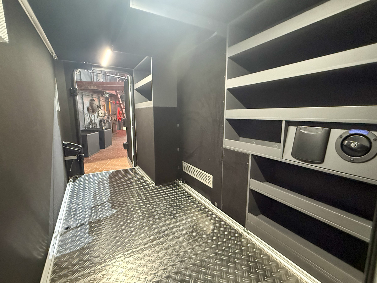 Garage storage area with shelving units and diamond-plate flooring in the Frankia Noctra Liner motorhome.