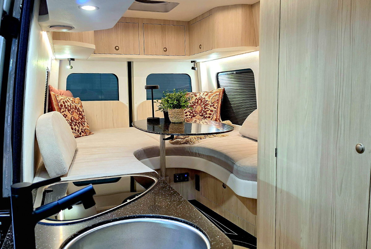 Innova Road Trip campervan interior with curved lounge bench seating, table and kitchen sink area