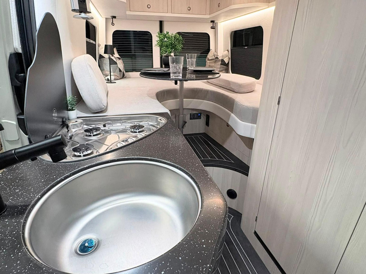 Toyota Innova Road Trip campervan kitchen with sink, hob and view of curved lounge seating area