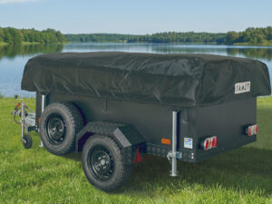 Jamet Offtrail folding trailer with black cover and all-terrain tyres parked on grass beside a lake