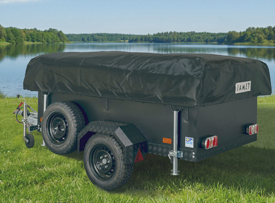 Jamet Offtrail folding trailer with black cover and all-terrain tyres parked on grass beside a lake