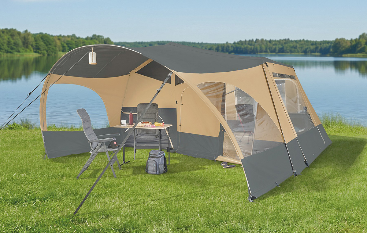 Jamet Offtrail folding trailer tent set up lakeside with camping chairs, table and open canopy on grass.