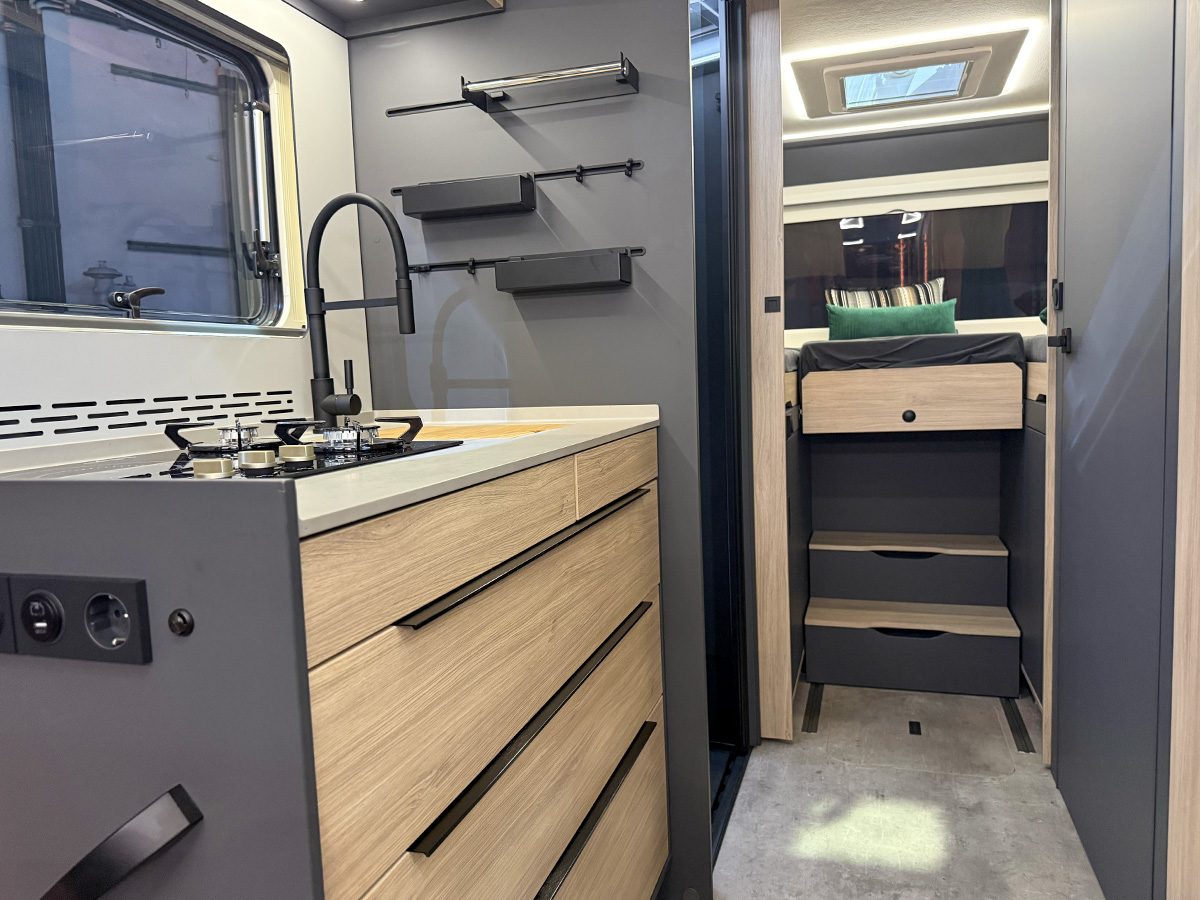 Kitchen with wooden drawers and hob in the Frankia Noctra Liner, leading to steps and rear sleeping area.
