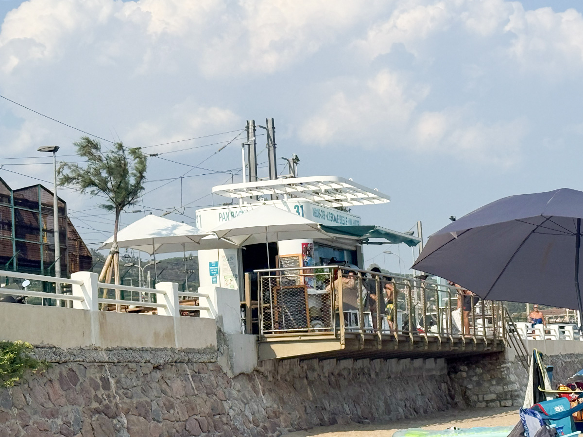 Beach kiosk "Pan Bagnat" on Cannes boulevard, near Camping Parc Bellevue, with sun umbrellas and seaside promenade.
