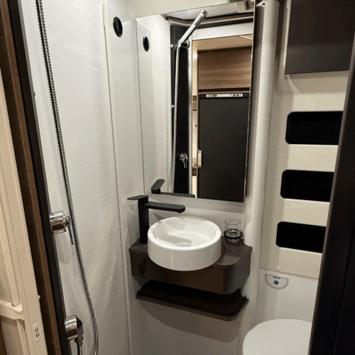Compact bathroom in the Rapido V64 camper van with round sink, shower head and toilet in a cassette layout.