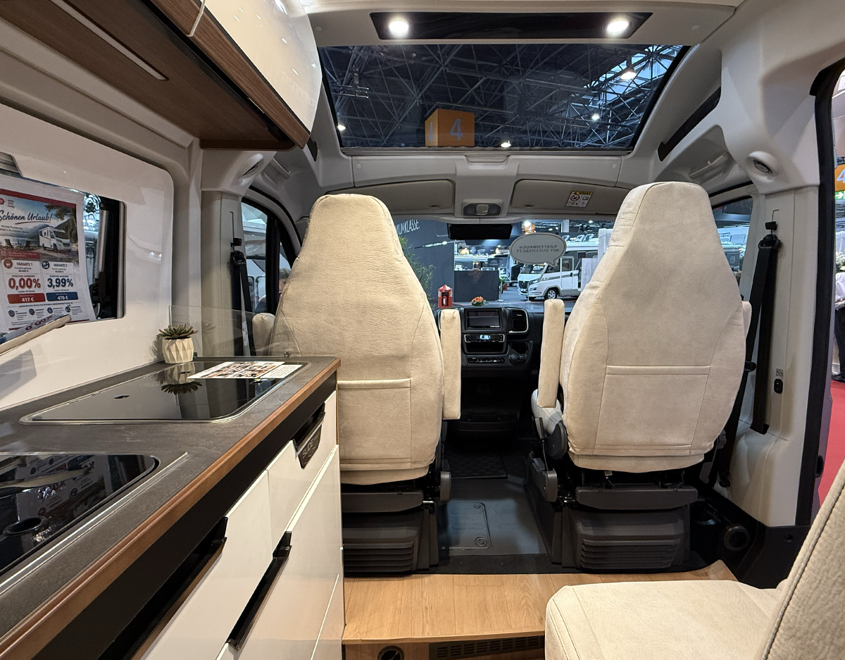 Rapido V64 camper van interior showing swivel cabin seats, kitchenette and panoramic roof at trade show