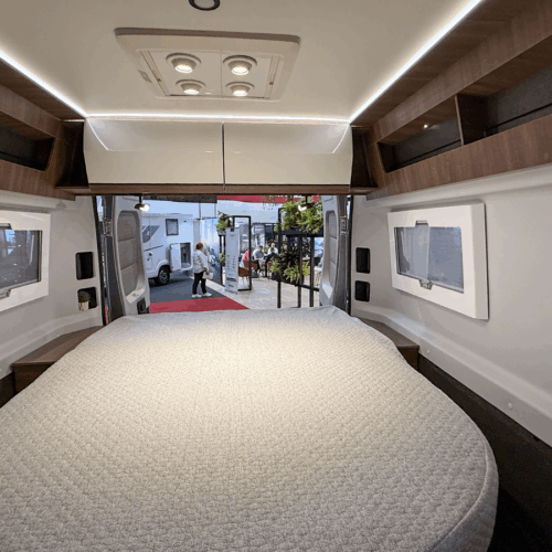 Rapido V64 motorhome interior showing island bed with overhead storage and rear window views
