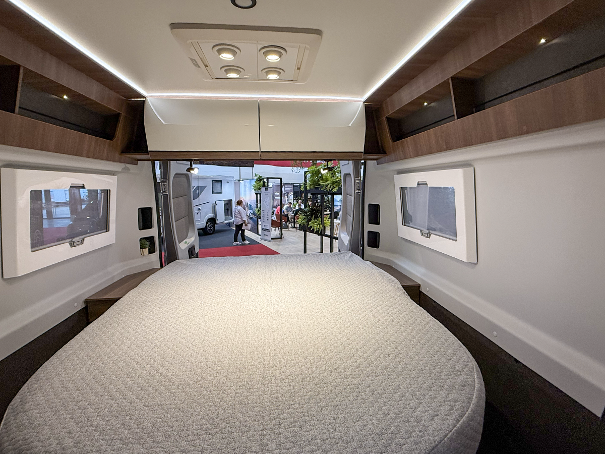 Rapido V64 motorhome interior showing island bed with overhead storage and rear window views