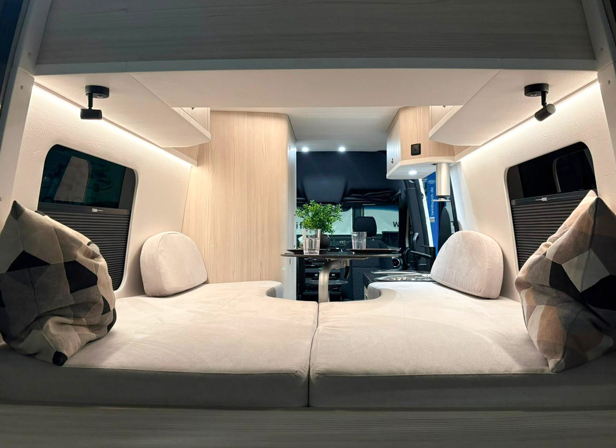 Toyota Innova Road Trip campervan interior showing rear lounge bench seating with cushions and front cab view