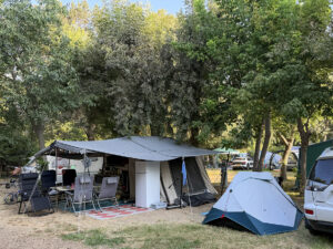 Camping pitch with awning, chairs and small tent among trees at Camping Parc Bellevue, Cannes