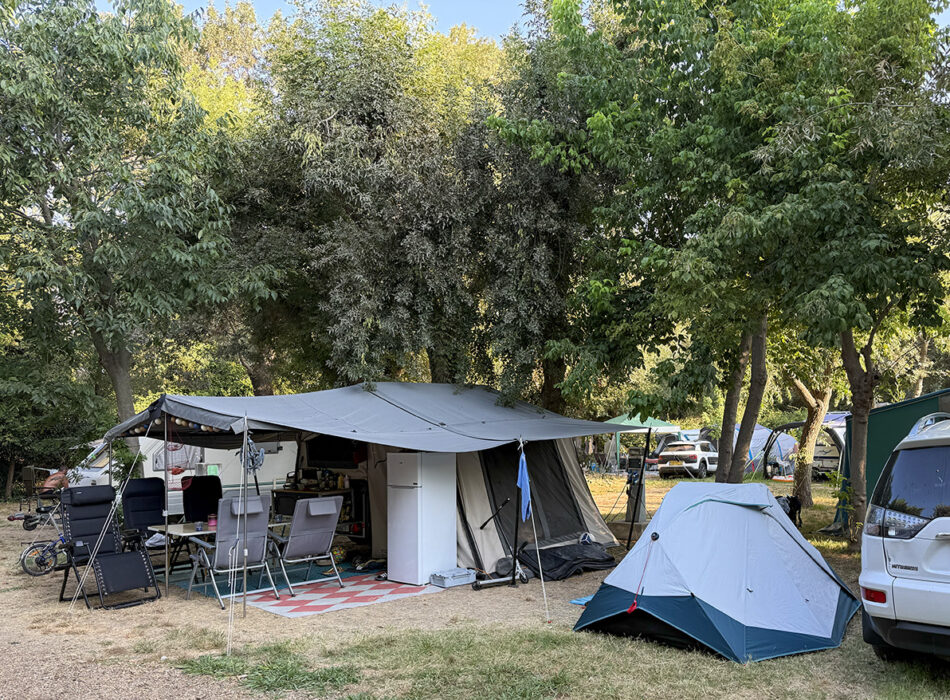 Camping pitch with awning, chairs and small tent among trees at Camping Parc Bellevue, Cannes