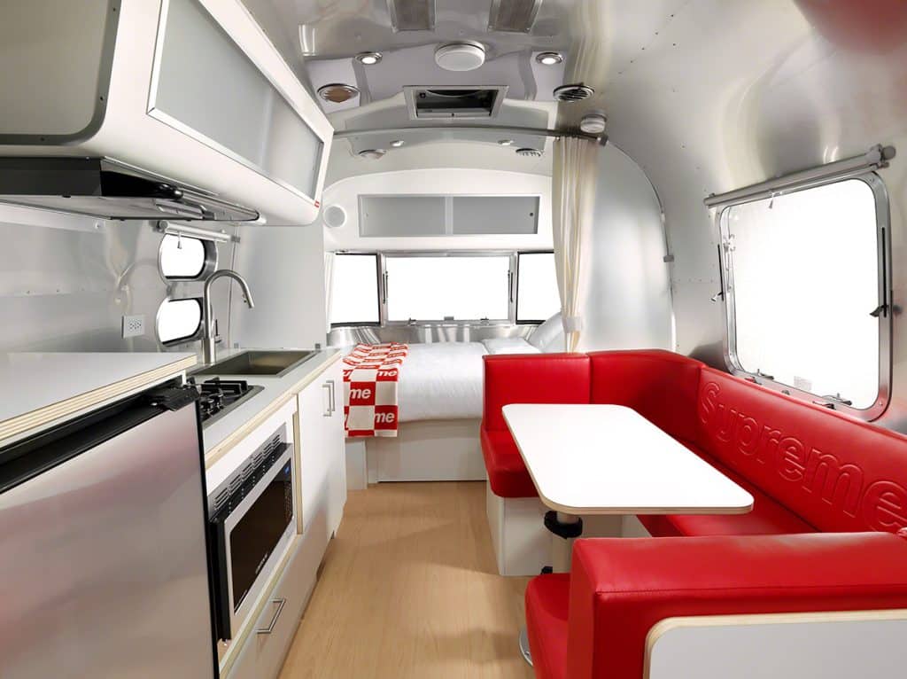 Erling Haaland Airstream interior with red Supreme-branded booth seating, white table and kitchenette