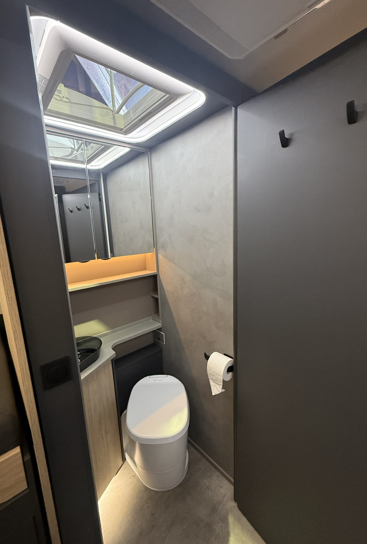 Compact bathroom in the Frankia Noctra Liner with skylight, toilet, sink and toilet roll holder.